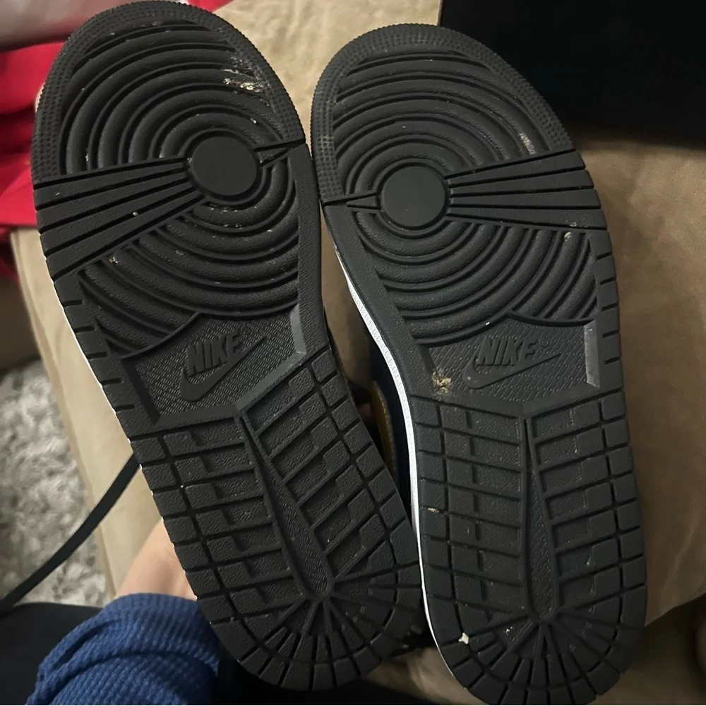 Nike Air Jordan 1 Mid in the black, metallic gold, and white colorway